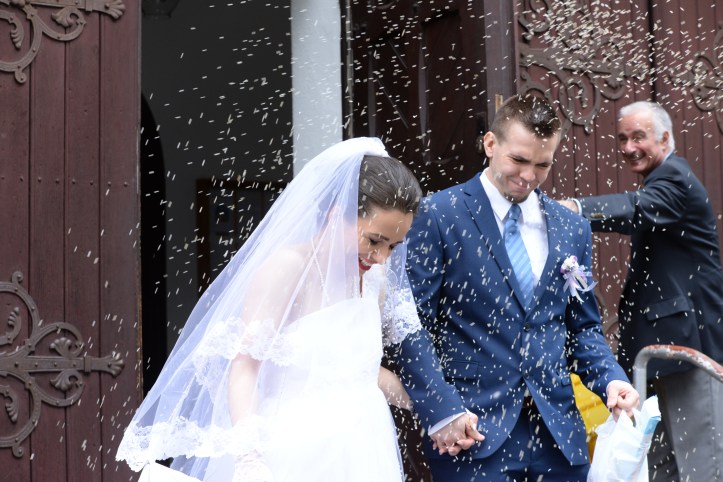 The bridal couple being thrown with rice after leaving the church