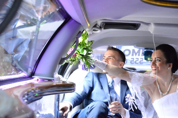 Bride waving her window out of the limousine