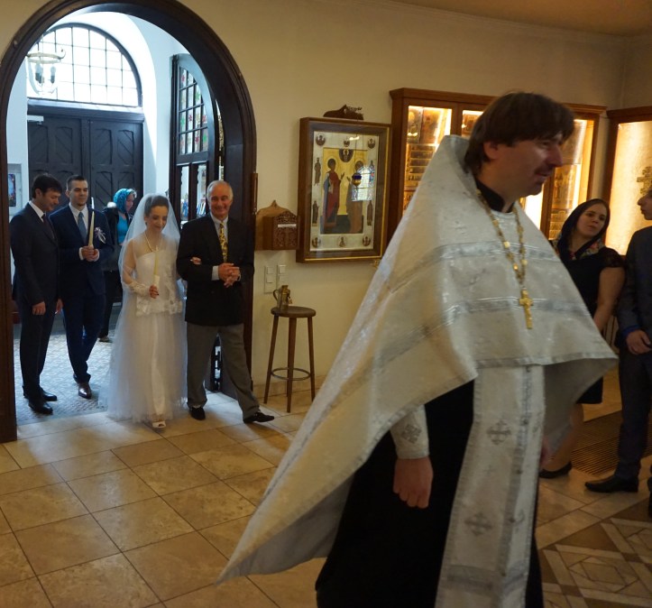 The priest ushering bride and groom into the main hall.