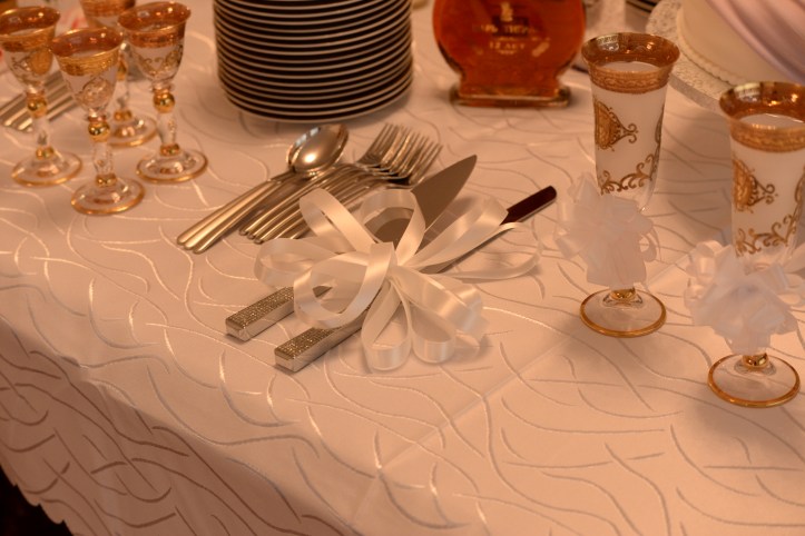 Ribbons as wedding decor for glasses and cake cutting utensils