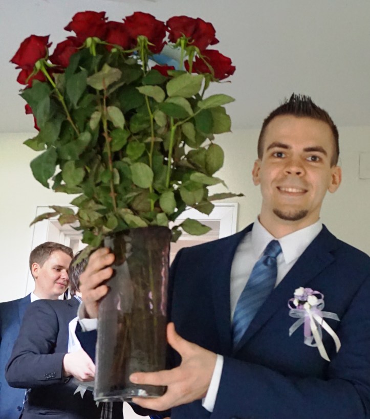 The groom carrying a bouquet of roses
