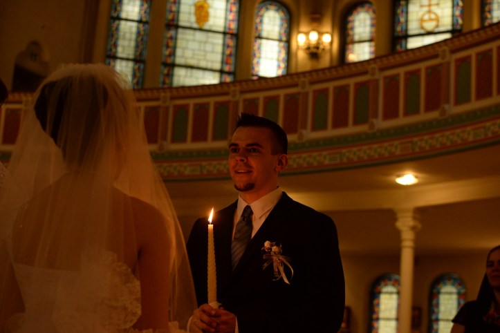 The groom holding a candle and speaking his marriage-vow