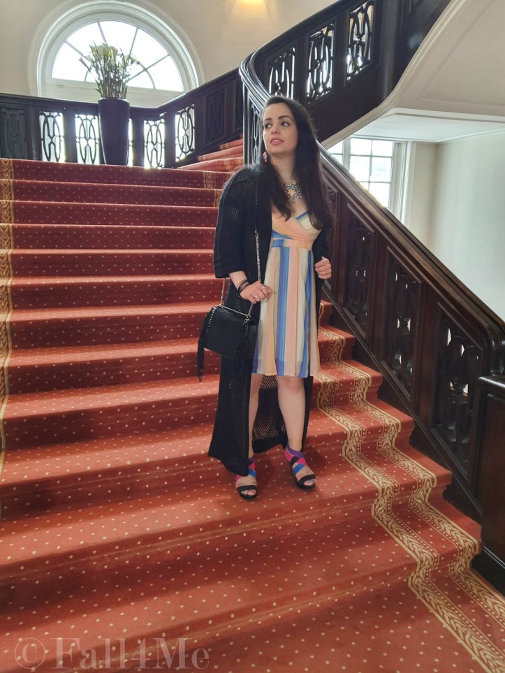 A dress with the colors of the sky under a black summer knit-cardigan and with a fringed bag.