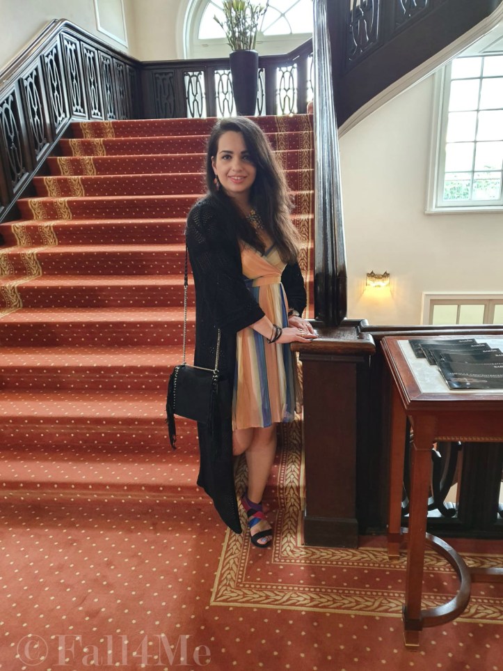 A dress with the colors of the sky under a black summer knit-cardigan and with a fringed bag.