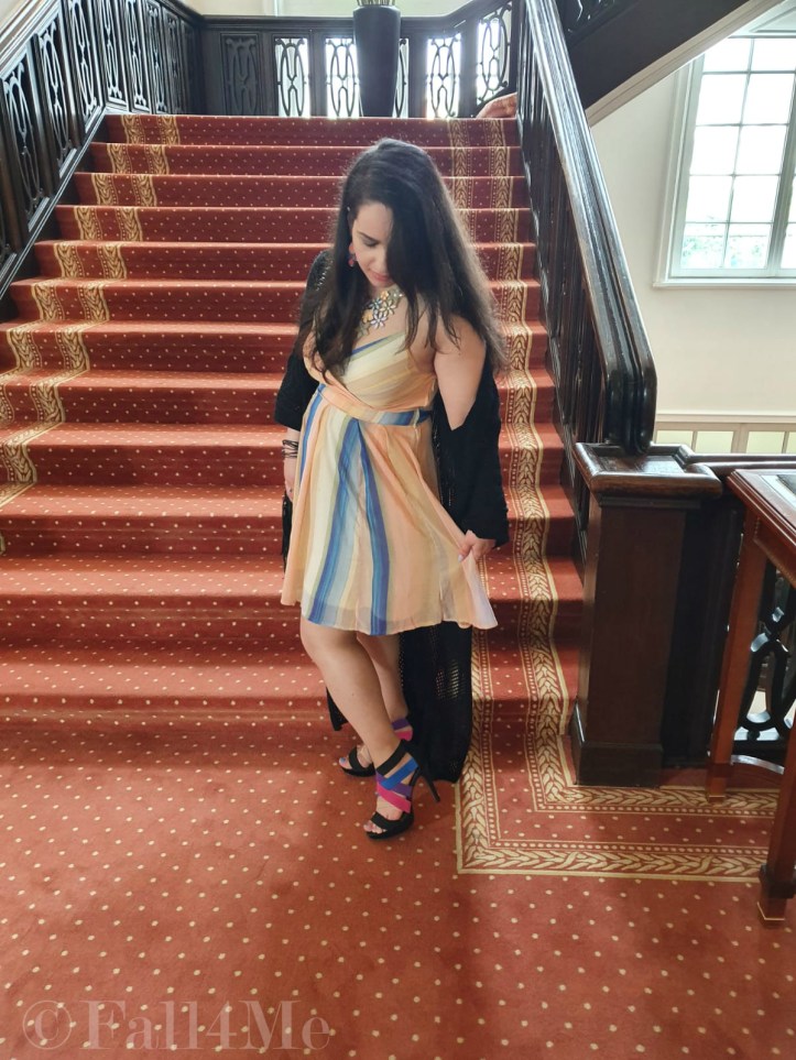 A dress with the colors of the sky under a black summer knit-cardigan and with a fringed bag.