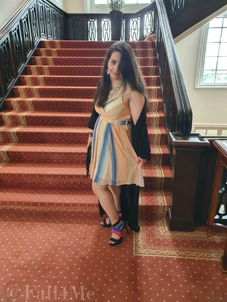 A dress with the colors of the sky under a black summer knit-cardigan and with a fringed bag.