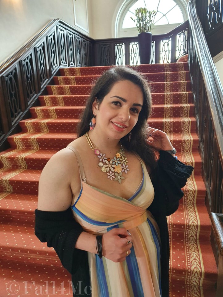 A dress with the colors of the sky under a black summer knit-cardigan and with a fringed bag.