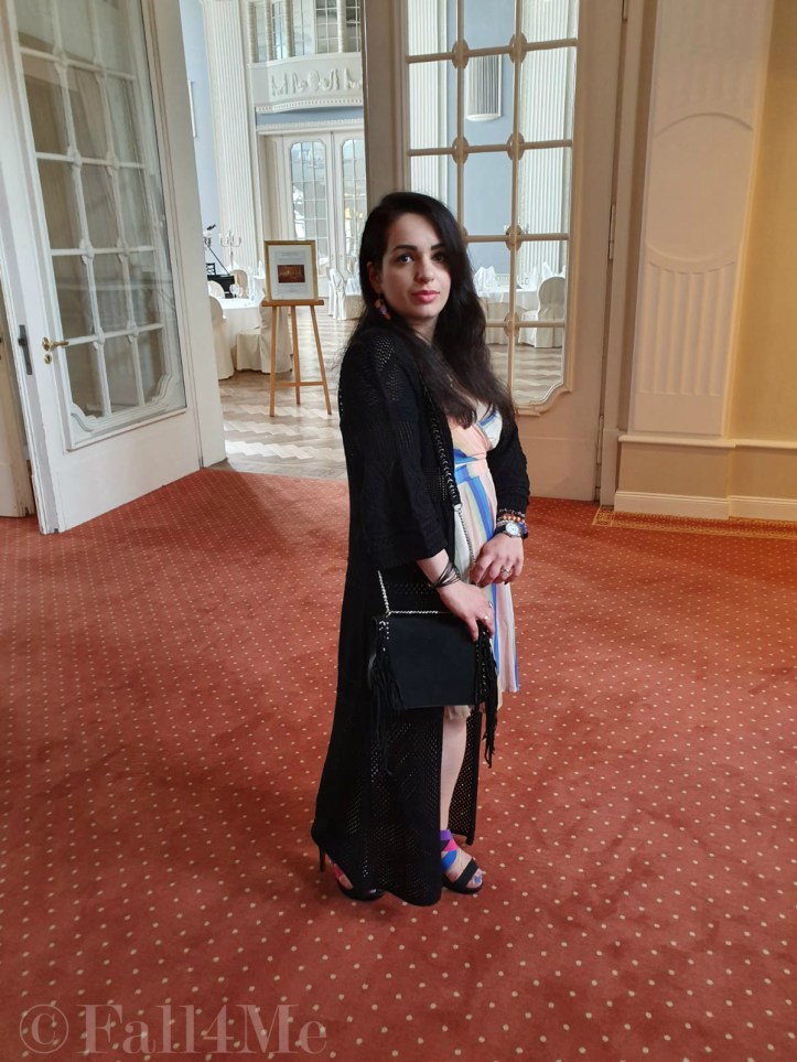 A dress with the colors of the sky under a black summer knit-cardigan and with a fringed bag.