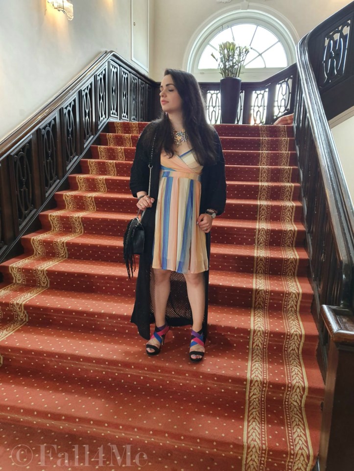 A dress with the colors of the sky under a black summer knit-cardigan and with a fringed bag.