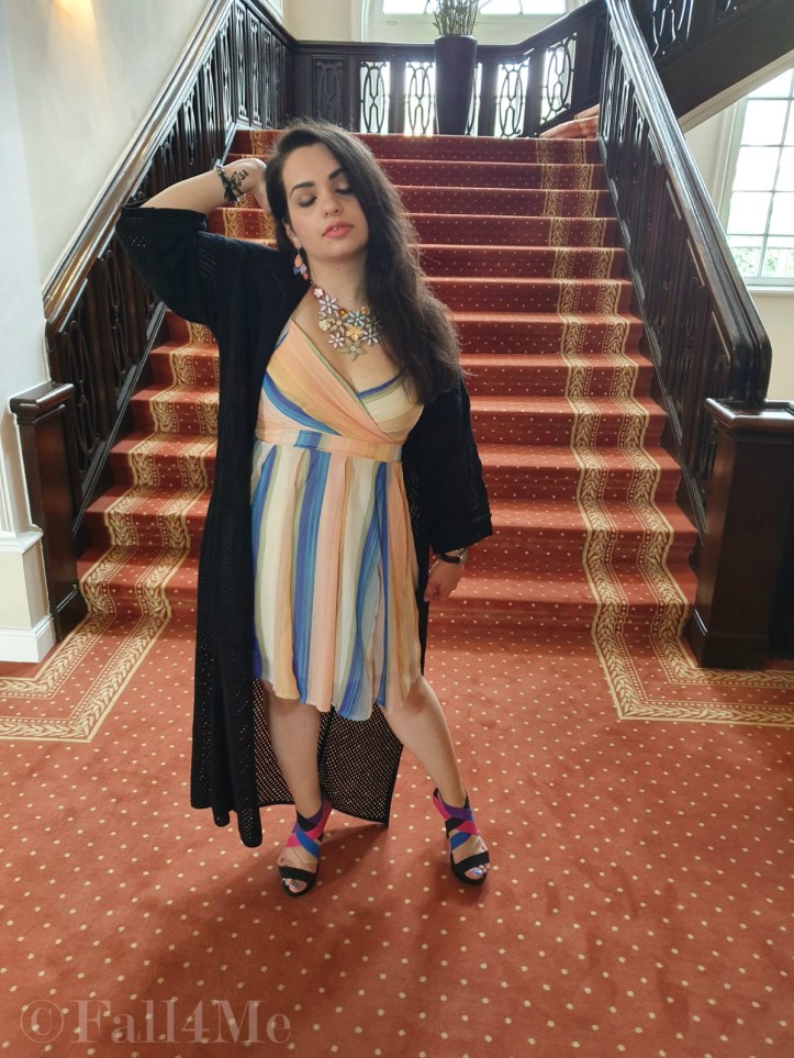 A dress with the colors of the sky under a black summer knit-cardigan and with a fringed bag.