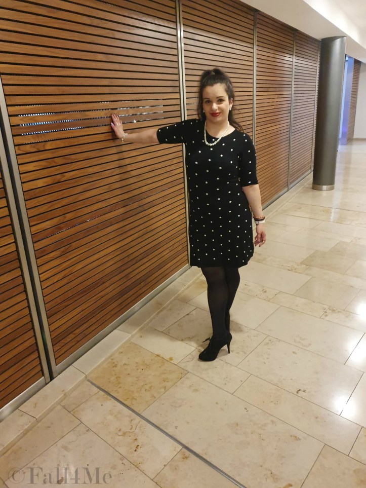 A black dress with white polka-dots combined with pearls and red lips.