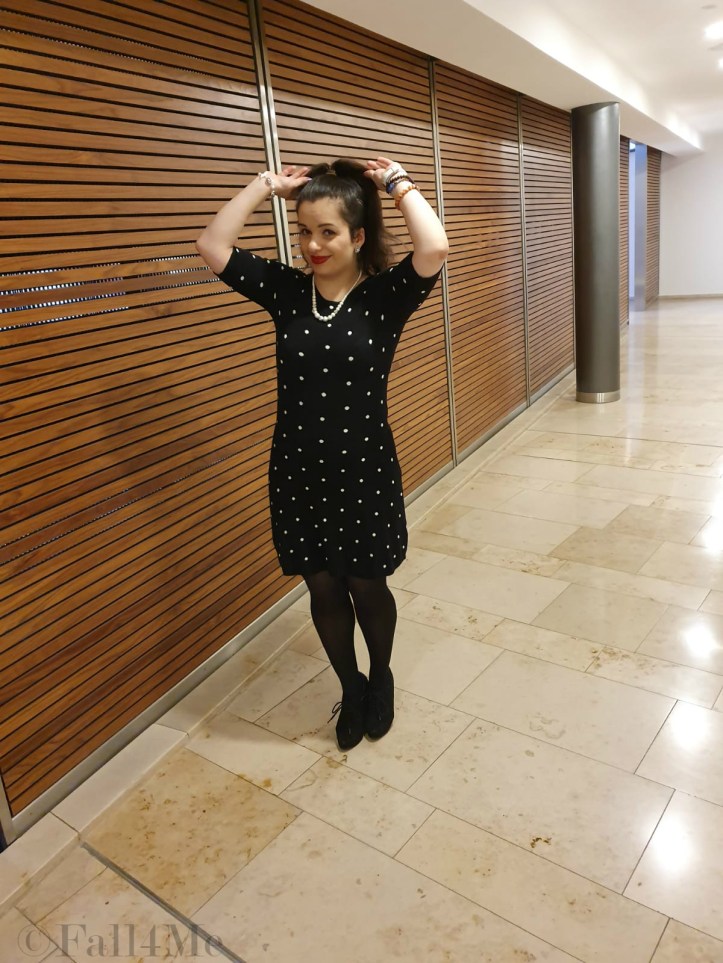 A black dress with white polka-dots combined with pearls and red lips.