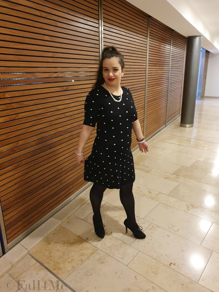 A black dress with white polka-dots combined with pearls and red lips.
