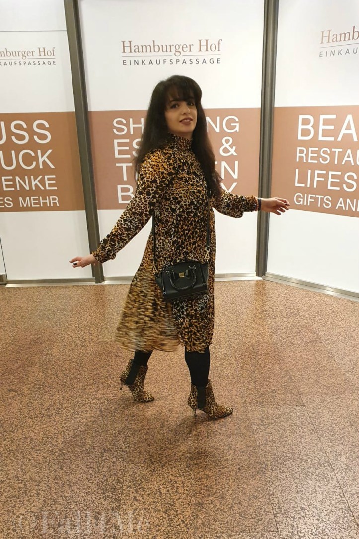 A leo-print dress styled with corresponding ankle boots and black accessories.