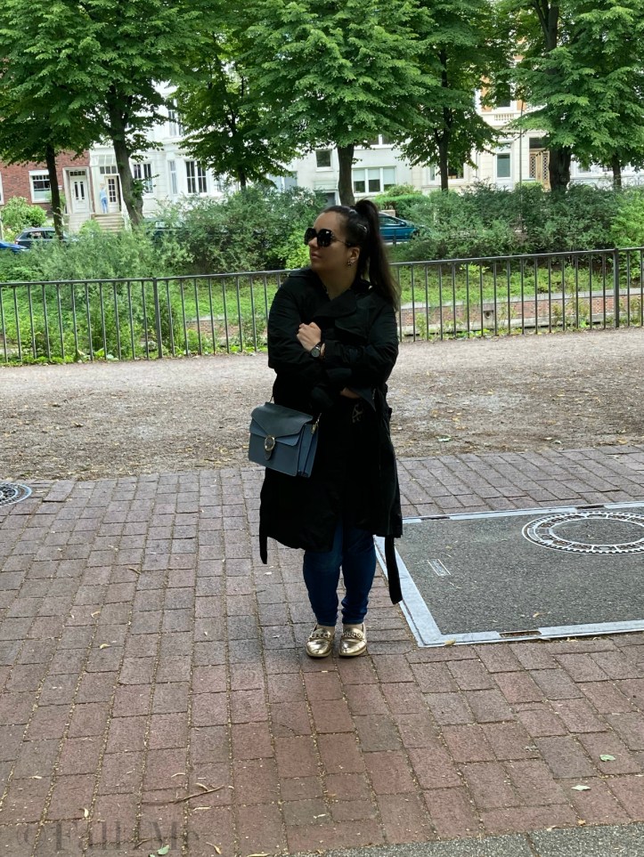 A black trench coat worn with skinny jeans and a leopard printed blouse.