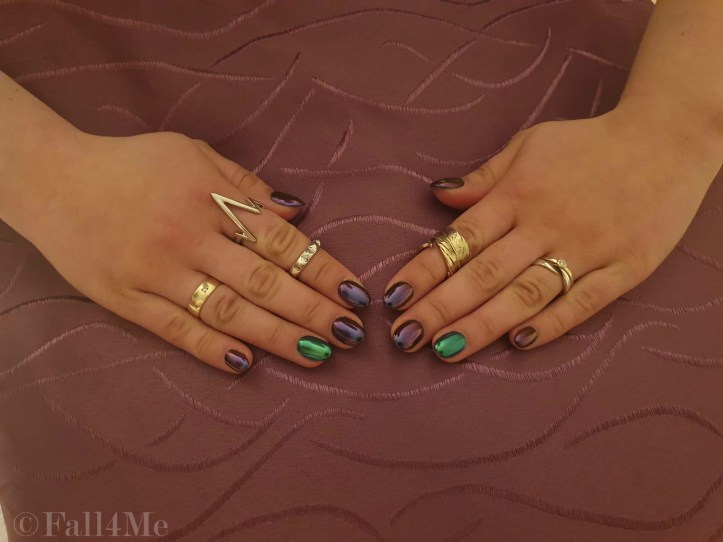 Chrome nails in purple and green on the ring fingers.