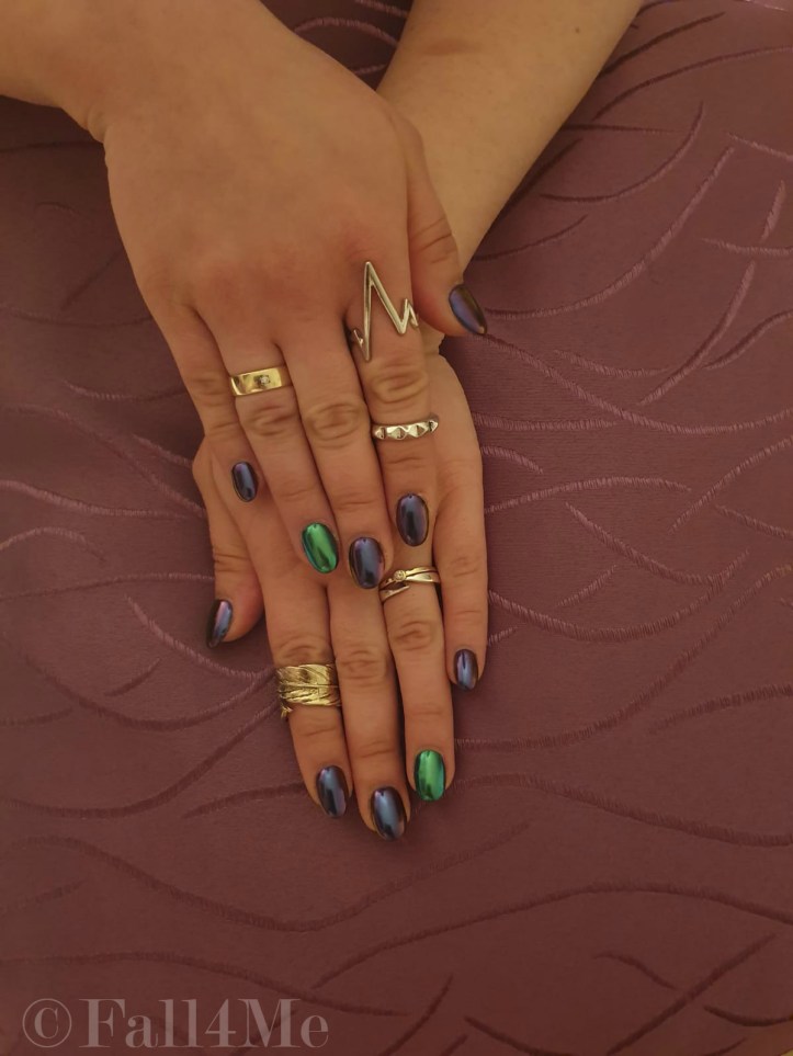 Chrome nails in purple and green on the ring fingers.