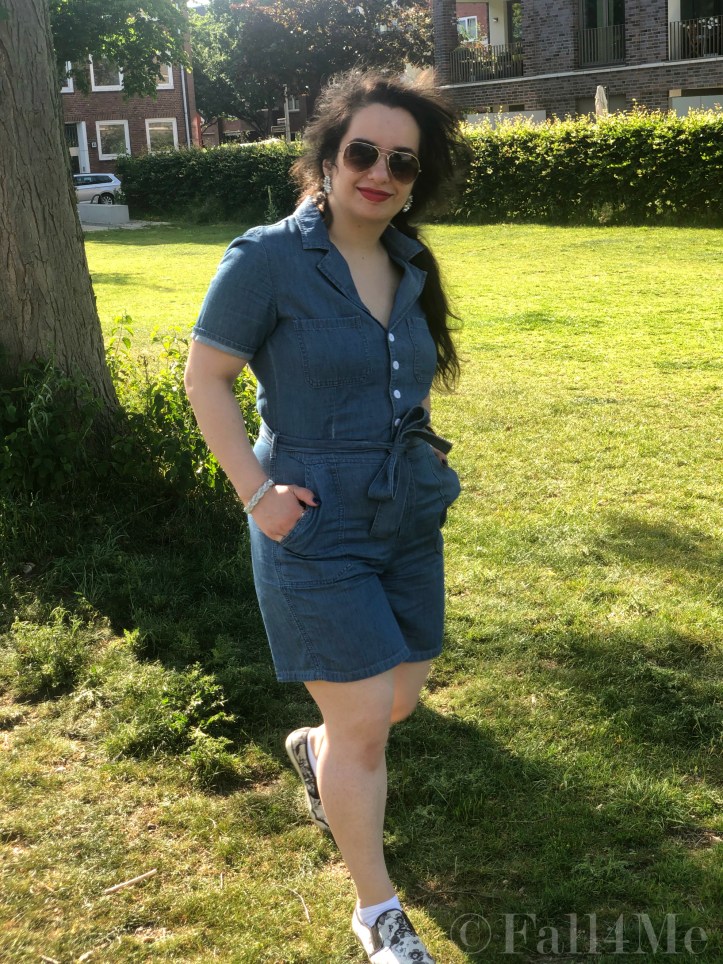 A denim jumpsuit combined with white leather accessories, silver jewellery and a red lipstick.