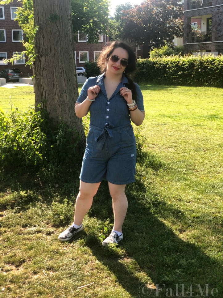 A denim jumpsuit combined with white leather accessories, silver jewellery and a red lipstick.