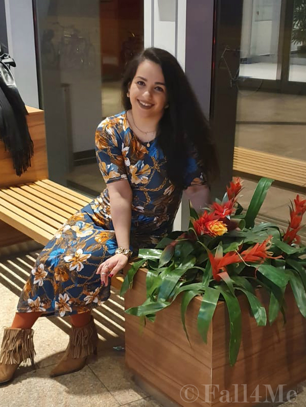 A turquoise dress with flowers in shades of cognac and golden accessories.