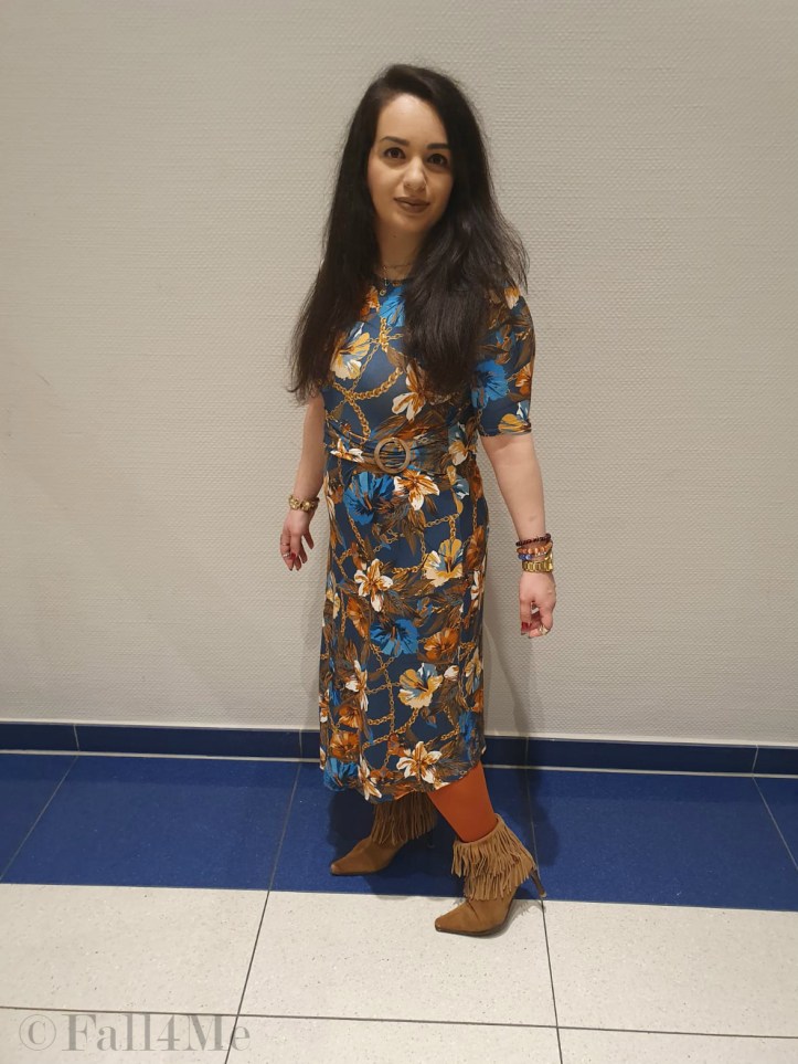 A turquoise dress with flowers in shades of cognac and golden accessories.