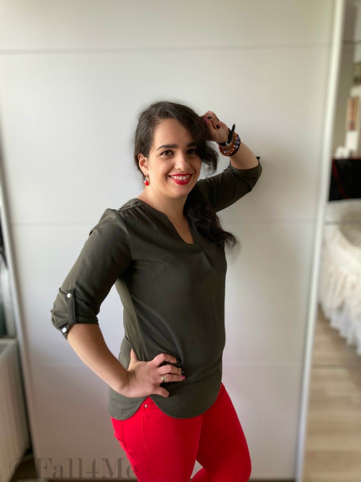 An olive green blouse combined with red lipstick and red skinny jeans and red chucks.