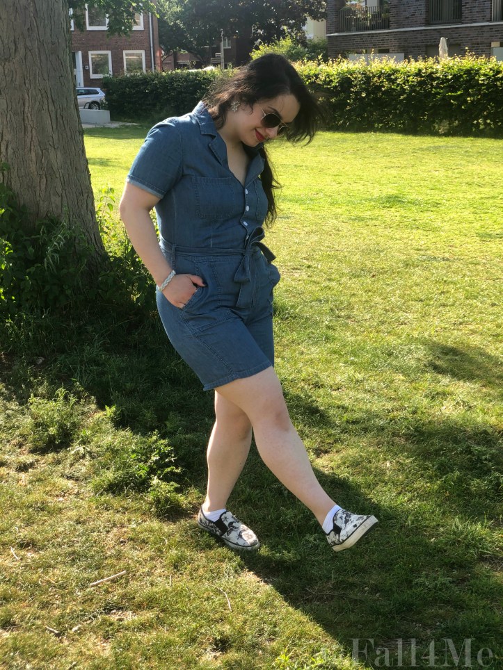 A denim jumpsuit combined with white leather accessories, silver jewellery and a red lipstick.