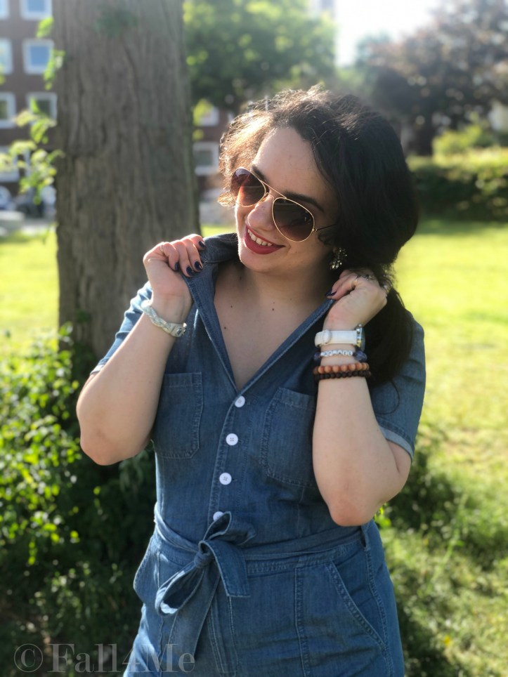 A denim jumpsuit combined with white leather accessories, silver jewellery and a red lipstick.
