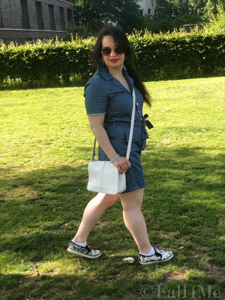 A denim jumpsuit combined with white leather accessories, silver jewellery and a red lipstick.