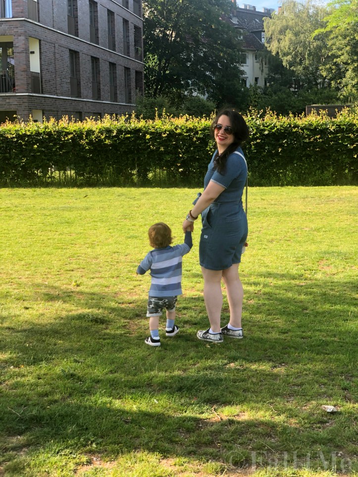 A denim jumpsuit combined with white leather accessories, silver jewellery and a red lipstick.