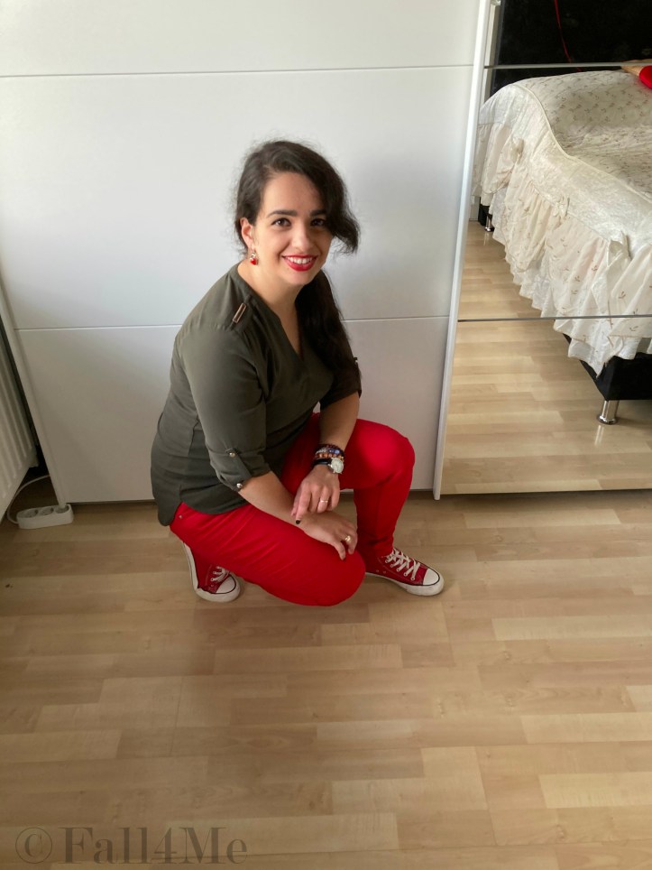 An olive green blouse combined with red lipstick and red skinny jeans and red chucks.