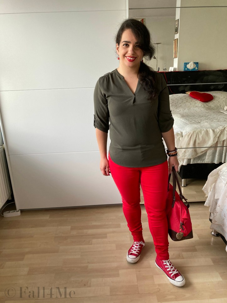 An olive green blouse combined with red lipstick and red skinny jeans and red chucks.