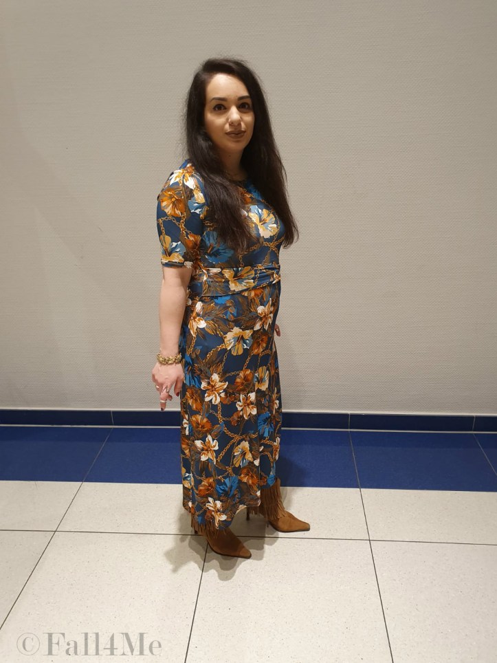 A turquoise dress with flowers in shades of cognac and golden accessories.