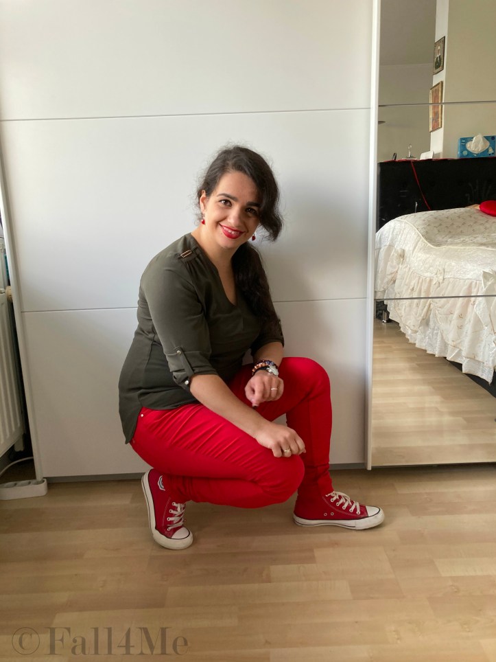 An olive green blouse combined with red lipstick and red skinny jeans and red chucks.