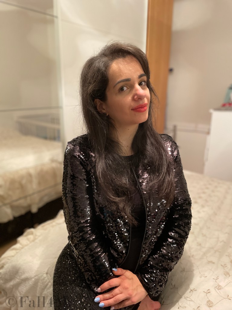 Powerdressing with orange make-up all in black with sequins and high heels.