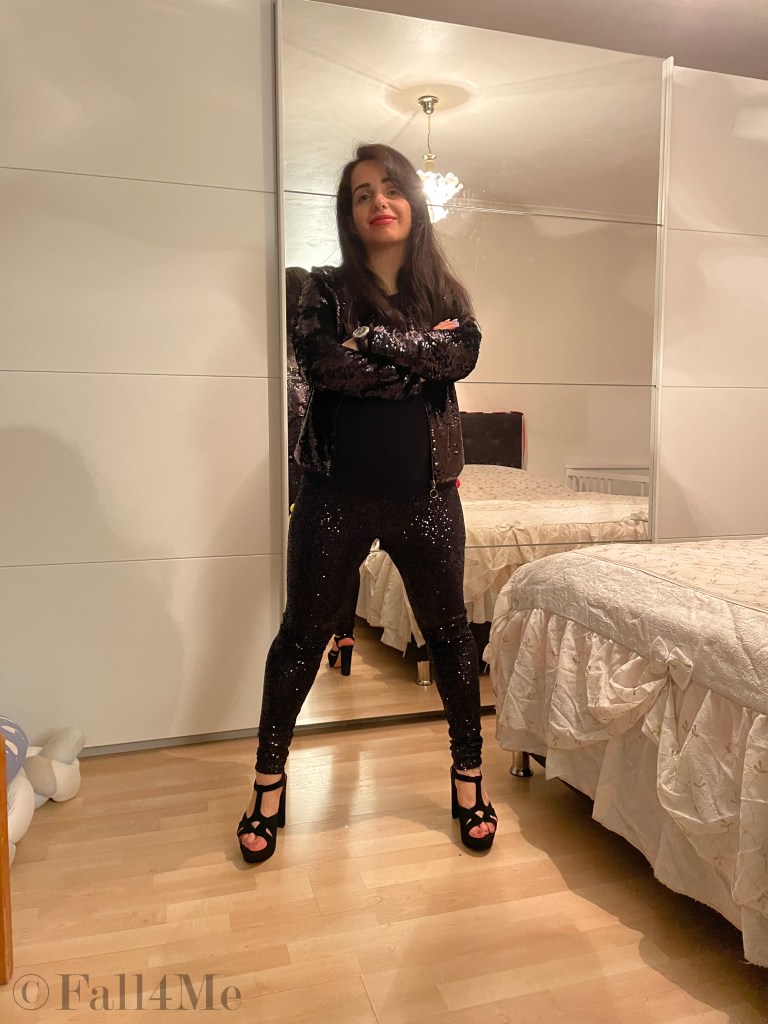 Powerdressing with orange make-up all in black with sequins and high heels.