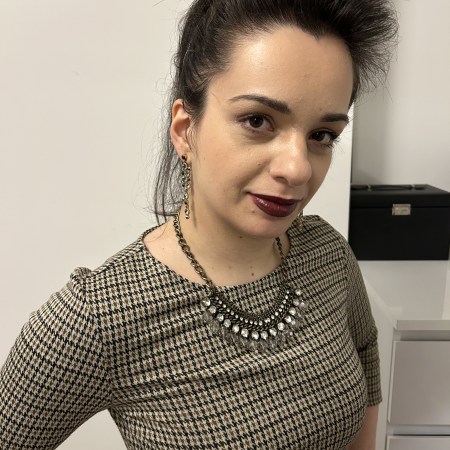 An outfit in corprate core pattern, figure hugging faux-leather leggings in dark green and overknees.