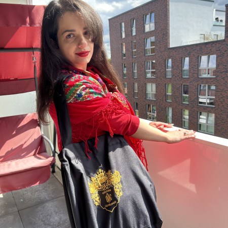 A red dress with a big ribbon worn with the accessory of the month a traditional Slavic/Baltic floral scarf, flats and a tote bag.