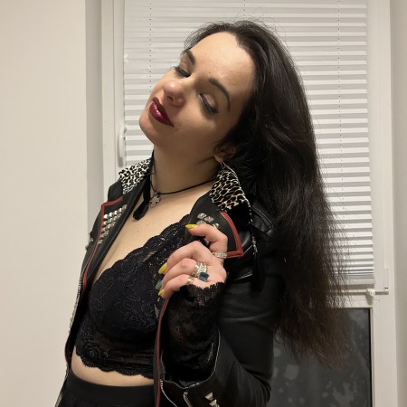 A bra worn as top under a leather-jacket that serves as a blazer with a skirt boots and a bag.