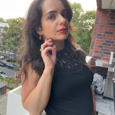 A gold-glitter pleated skirt worn with a black shirt and black/brown loafers